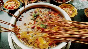 A large pot of soup with various ingredients and chopsticks. - Shangshanju Yangxin Chanjing Hotel (Leshan)