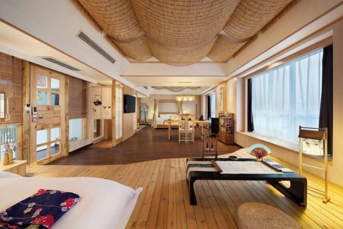 Ein Hotelzimmer mit einem großen Bett, einem Schreibtisch, einem Stuhl und Blick ins Freie.
