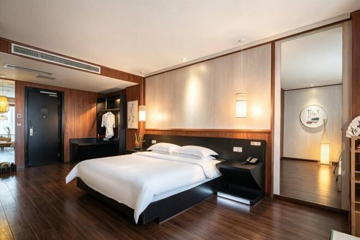 Ein modernes Hotelzimmer mit einem großen Bett, Nachttischen, einem Kleiderschrank und einer Wandlampe.