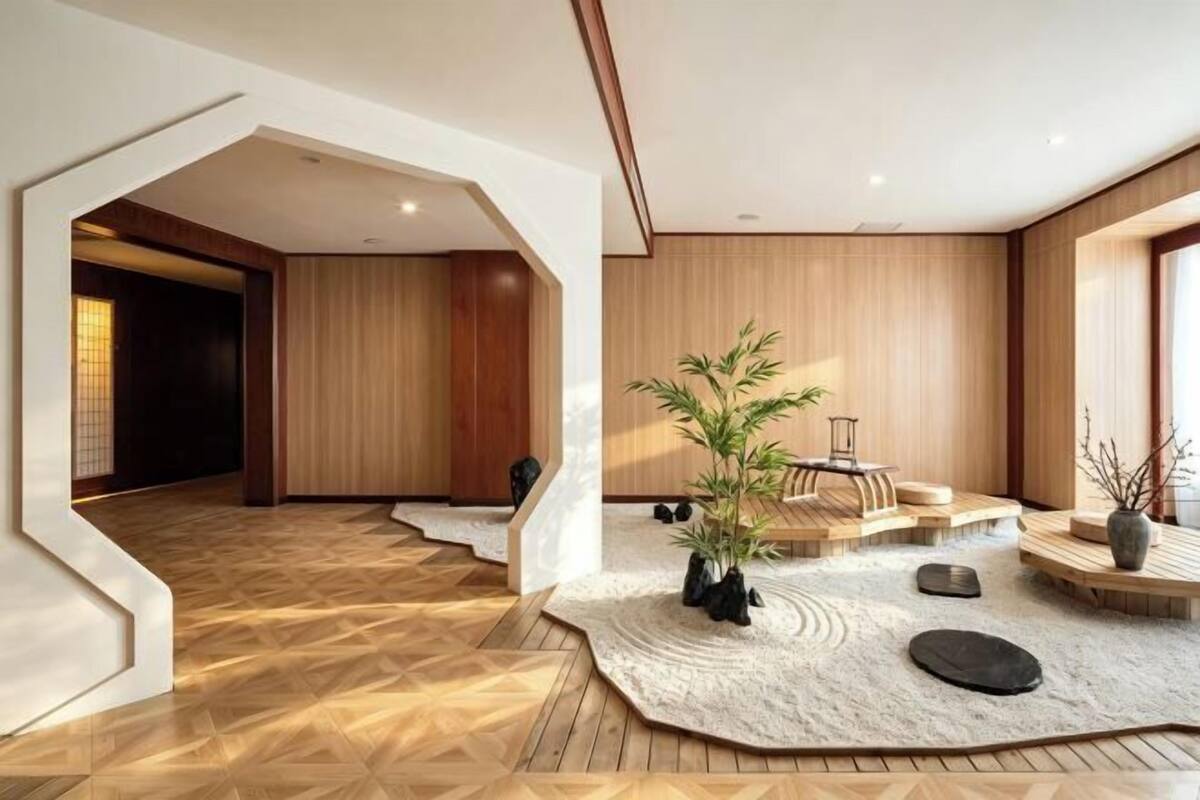 Ein modernes Interieur mit Holzboden, einer zentralen Sitzecke mit Pflanze und einer markanten architektonischen Arkade.