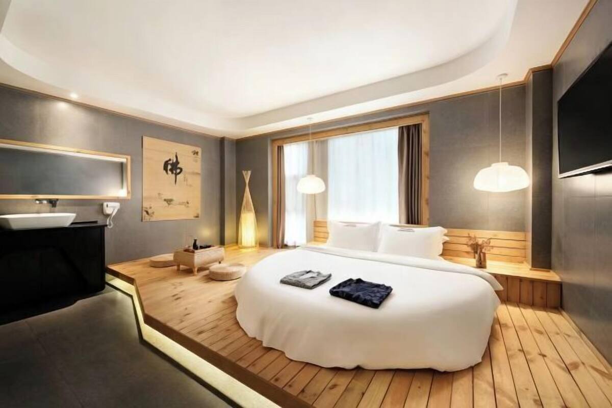 Ein modernes Schlafzimmer mit einem großen Bett, Nachttischen, einem Schminktisch und einem großen Fenster.