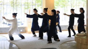 A group of people practicing martial arts in a room with large windows and a wooden floor. - Shangshanju Yangxin Chanjing Hotel (Leshan)