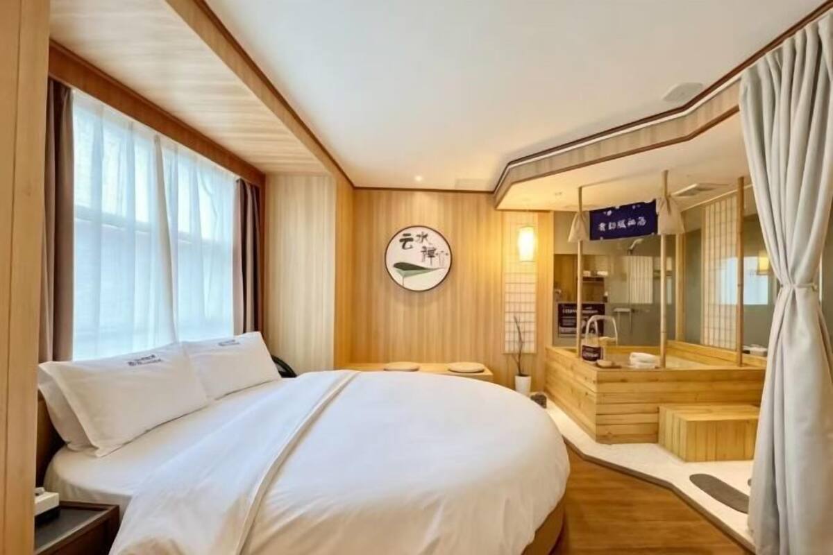 Una habitación de hotel con una cama, un escritorio pequeño, un espejo y una ventana.