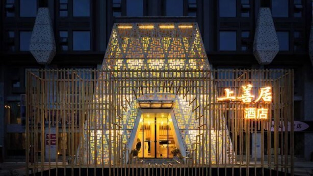 A hotel entrance with a distinctive geometric facade and illuminated signage. - Shangshanju Yangxin Chanjing Hotel (Leshan)