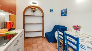 Cocina compacta con cafetera, un lavabo y un pequeño comedor con mesa y sillas.