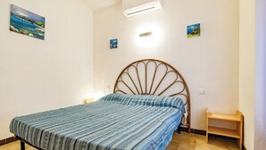 Un dormitorio con una cama, aire acondicionado de pared y dos mesitas de noche.