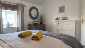 A bedroom with a bed, a dresser, a mirror, and a 'FAMILY' sign on the wall. - Idyllic Cottage Sleeps 4 pet Friendly (Appleby-in-Westmorland)
