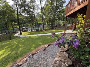 A landscaped garden with a pathway, a gazebo, and a view of a lake.