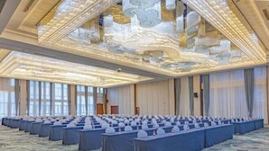 A conference room with rows of tables, a patterned carpet, and a decorative ceiling.