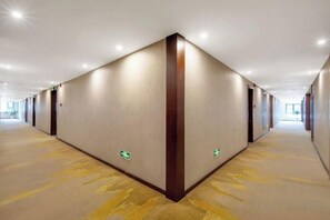 A long, narrow hotel corridor with a carpeted floor, walls with a vertical wooden accent, and emergency exit signs. - Weiye Hotel (Pan'an)