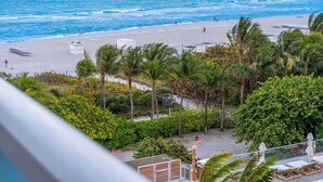 A beach view with palm trees, a sandy beach, and a clear blue ocean.