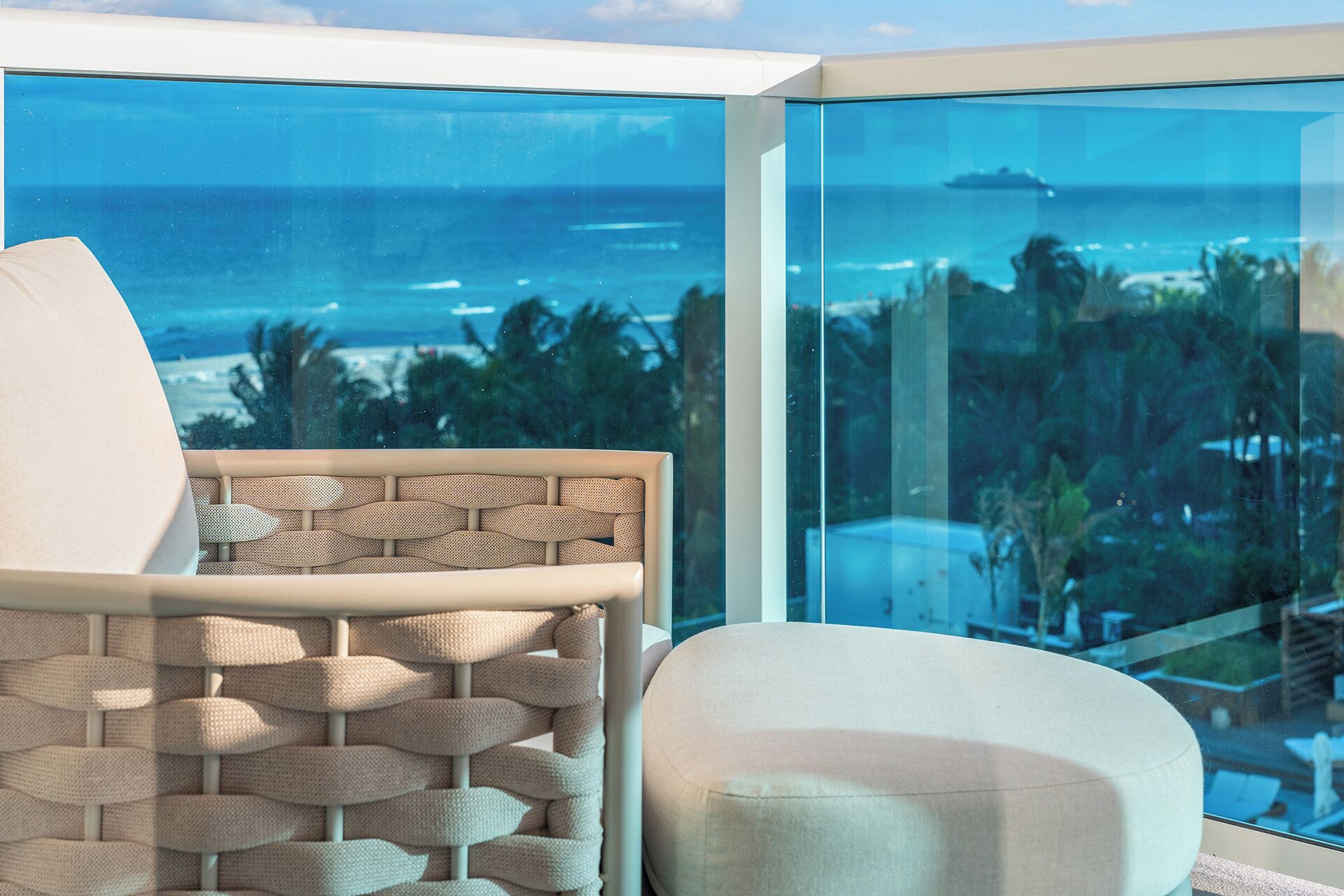 A balcony with a view of the ocean and palm trees.
