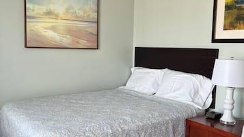 A hotel room with a bed, a nightstand, a lamp, and two framed pictures on the wall.