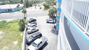 A parking area with multiple cars, a building with a blue and white facade, and a clear view of the surrounding area. - OCEAN VIEW Studio@Daytona Zzz 4 (Daytona Beach)
