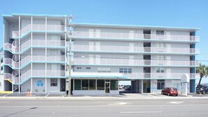 A multi-story hotel with a blue and white color scheme, a visible entrance, and a parking lot with cars. - OCEAN VIEW Studio@Daytona Zzz 4 (Daytona Beach)