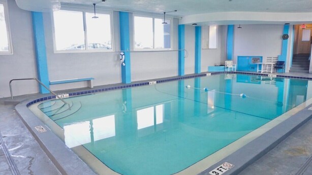 An indoor swimming pool with clear water, a diving board, and a lifeguard chair. - OCEAN VIEW Studio@Daytona Zzz 4 (Daytona Beach)