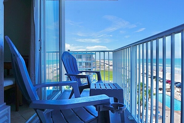Un balcone con vista sulla spiaggia e sull'oceano, con due poltrone Adirondack e un tavolino.