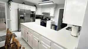 A modern kitchen with white cabinetry, stainless steel appliances, and a central island. - 6 Kings Ping-Pong Gazebo! (Northbrook)