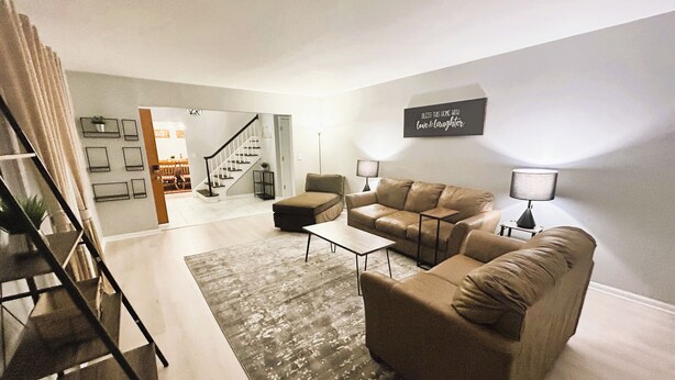 A modern living room with a sofa, coffee table, and lamps. A staircase is visible in the background. - 6 Kings Ping-Pong Gazebo! (Northbrook)