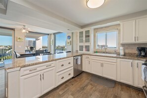 Una cocina moderna con gabinetes blancos, encimeras de granito y lavavajillas empotrado.