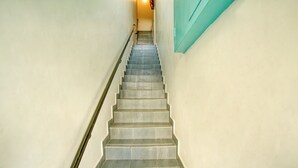A staircase with a handrail, leading to a landing with a teal-colored wall. - Daffodils by La Maison Charu  (Puducherry)
