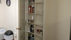 Uma despensa com prateleiras repletas de diversos alimentos e produtos de limpeza.