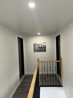 Un pasillo con barandilla de madera y una fotografía blanco y negro en la pared.