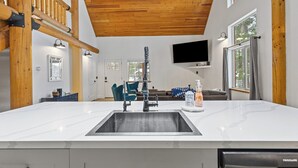 Een moderne keuken met een ruim kookeiland, houten balken in het plafond, een ingebouwde televisie en uitzicht op de omgeving.