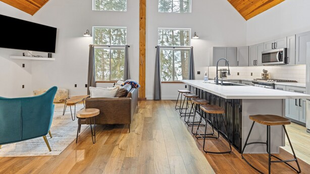 Een ruime keuken met een groot eiland, barstoelen en een houten plafond.