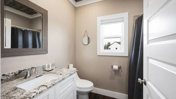 A bathroom with a white sink, mirror, and toilet.