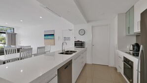 A modern kitchen with white cabinetry, a built-in microwave, and a stainless steel sink.