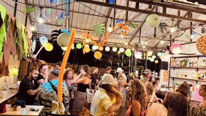 Un événement en intérieur très fréquenté, où les gens se côtoient, avec des tables où sont servis des boissons et des guirlandes lumineuses décoratives.