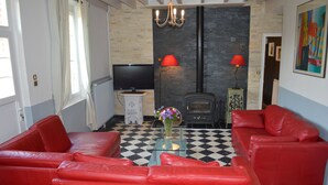 Ein Wohnzimmer mit roten Ledersofas, einem Glastisch, einem Flachbildfernseher, einem Kamin und einem Schachbrettmuster-Boden.