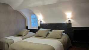 Ein Hotelzimmer mit zwei Betten, einer Wand aus Steinoptik und einem Fenster mit Tageslicht.