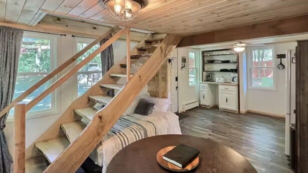 A wooden interior with a staircase, a cozy seating area, and a kitchen. - Cozy Cabin with Fireplace, Firepit, Close to Lake (Hawley)