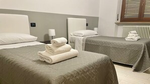 A hotel room with two beds, each with a grey quilted bedspread and white pillows. There is a stack of folded white towels on the left bed. - INTERO APPARTAMENTO NEL CUORE DEL CENTRO STORICO DI VERONA (Verona)
