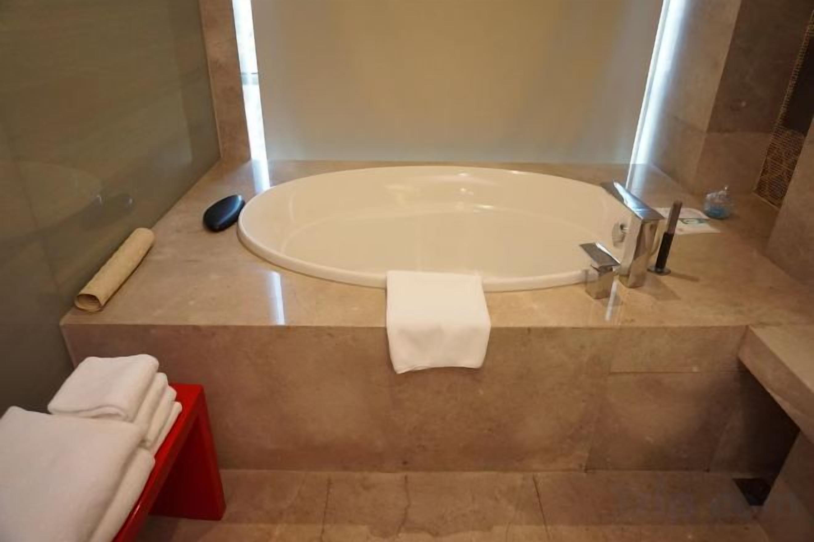 A bathroom with a large bathtub, a towel rack, and a red towel stand.
