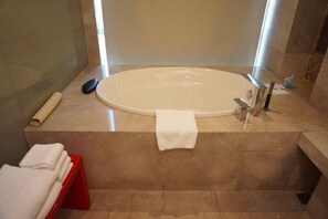 Ein Badezimmer mit einer großen Badewanne, einem Handtuchhalter und einem roten Handtuchständer.