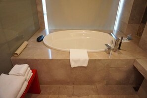 Une salle de bain avec une grande baignoire, un porte-serviettes rouge et une serviette blanche sur le sol.