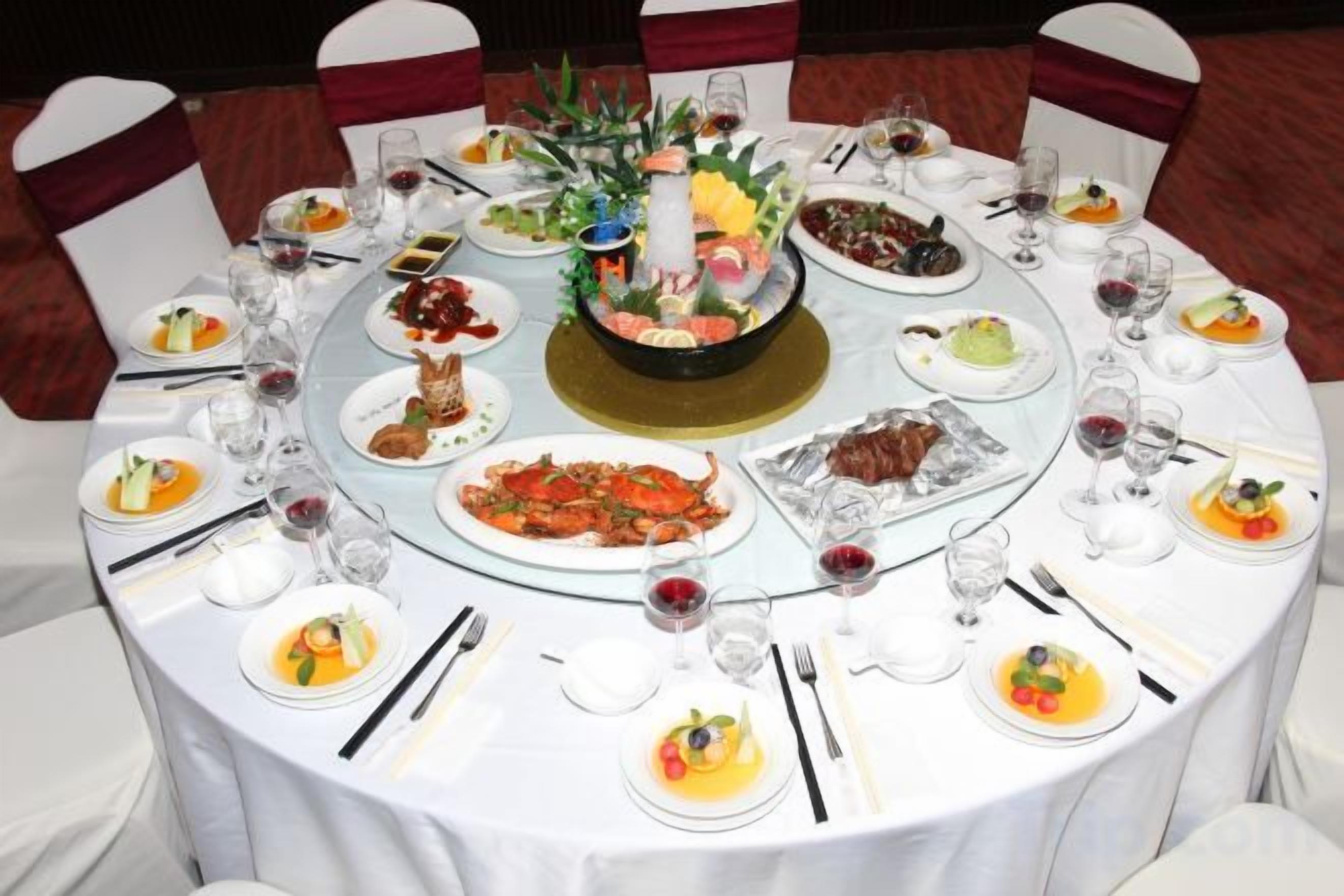 A round dining table with multiple plates of food, glasses, and cutlery.