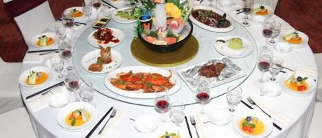 A round dining table with multiple plates of food, glasses, and cutlery.