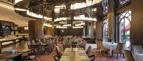 A restaurant with a long table, multiple chairs, and a chandelier.