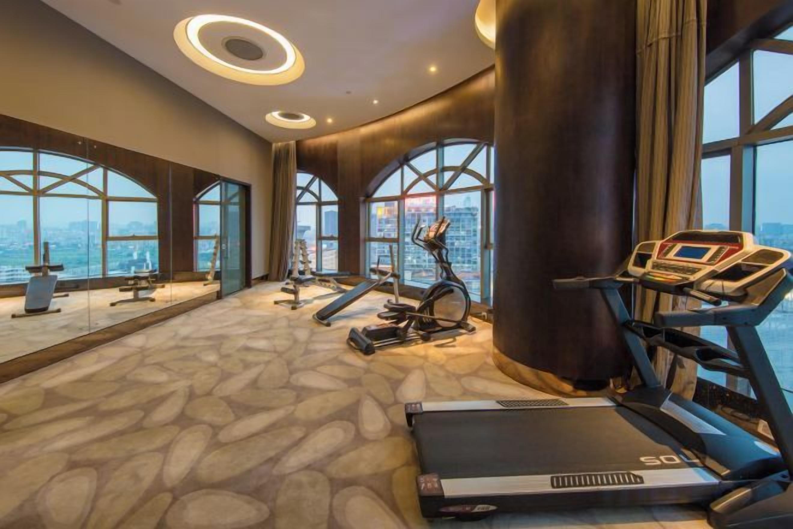 A gym with exercise equipment, large windows, and a city view.