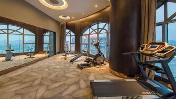 A gym with exercise equipment, large windows, and a city view.