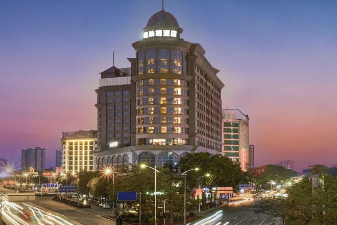 A multi-story hotel with a prominent corner tower, large windows, and a well-lit facade.