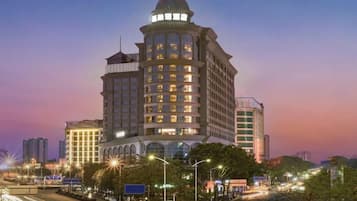 A multi-story hotel with a prominent corner tower, large windows, and a well-lit facade.