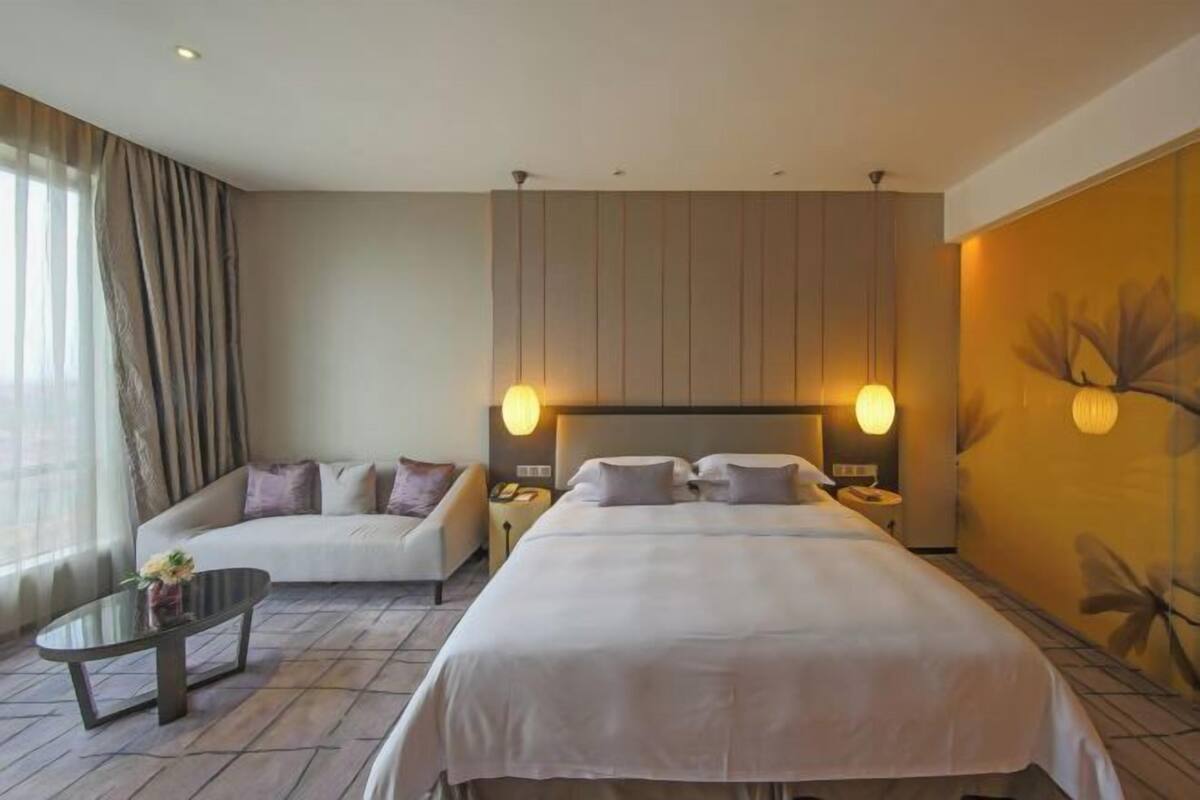 Een hotelkamer met een groot bed, een bank, een kleine tafel en een nachtkastje.