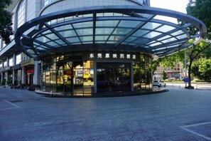 A modern building with a curved glass facade and a covered entrance. - Joyc Hotel Dongguan (Dongguan)