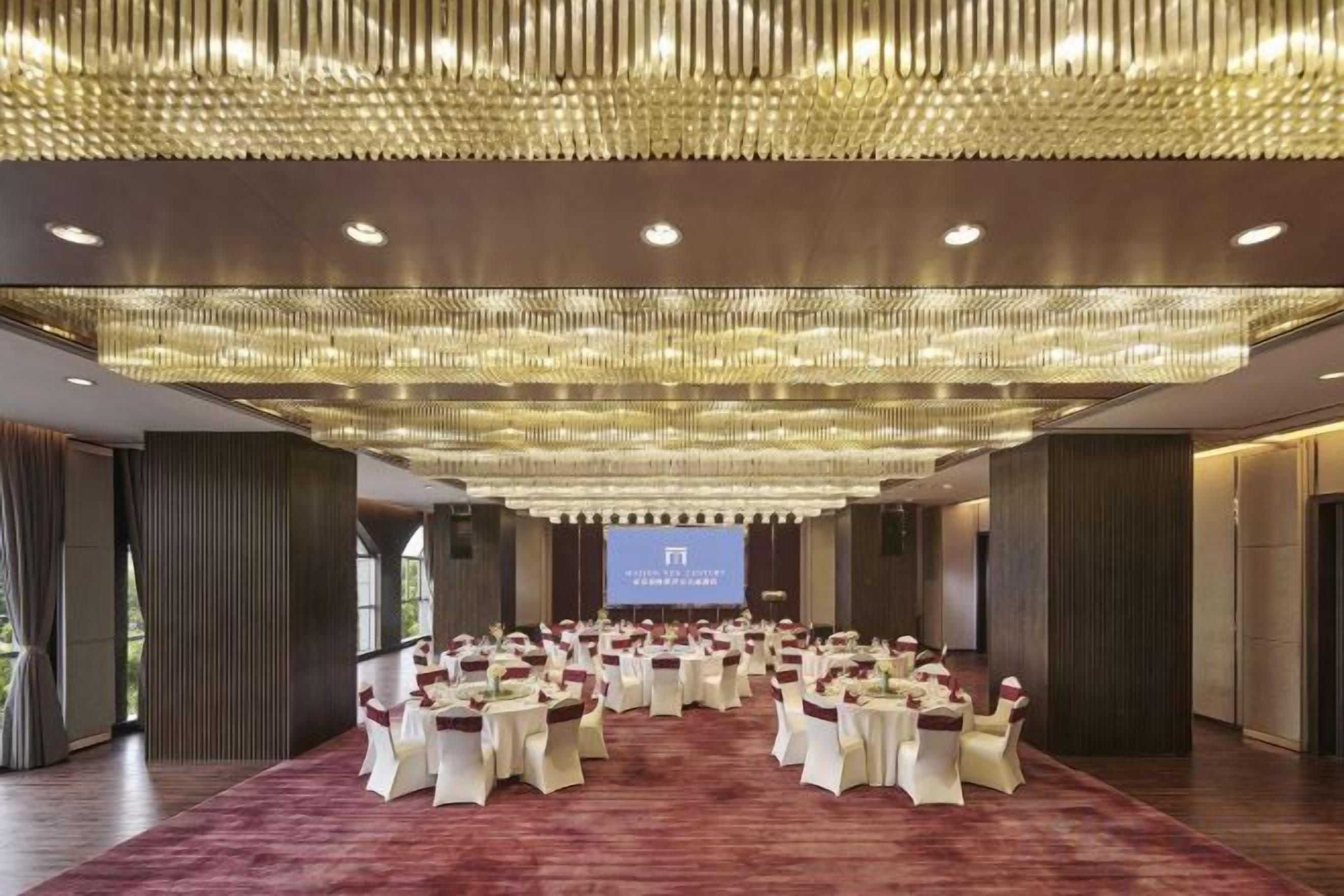 A conference room with a large screen, round tables, and chairs arranged for a meeting.
