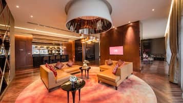 A modern hotel lobby with a circular seating area, a bar, and a large screen.